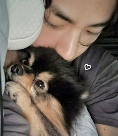 a woman laying in bed with her dog on top of her chest and head resting on the pillow