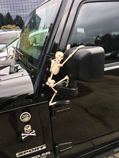 a skeleton sitting in the drivers side window of a truck