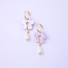 The Daisy Pearl Drops are elegant floral earrings that add a touch of class and polish to any outfit. Perfect for a fancy affair (wedding! date night!) or any occasion when you want to impress and glimmer! Hand-made in studio using beautiful marbled acrylic and glass pearls.  The drops hang from 18mm, 14 karat, gold-filled hoops and are removable so you can wear the hoops on their own—two earrings in one, perfect for travel! Uses 14 karat gold-filled hoops which are tarnish resistant and hypoallergenic Hand-made in New York City Feminine Drop Earrings For Anniversary, Feminine Drop Earrings For Anniversary Bridal, Feminine Drop Earrings For Bridal Anniversary, Feminine Bridal Drop Earrings For Anniversary, Feminine Flower Drop Earrings With Pearl Drop, Feminine Flower Shaped Pearl Drop Earrings, Elegant Purple Flower Earrings, Feminine Flower Dangle Earrings With Pearl Drop, Feminine Dangle Earrings For Anniversary