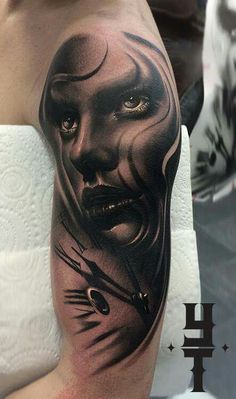 a man's arm with a black and grey tattoo on it, depicting the face of a woman