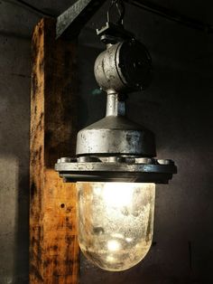 an old fashioned light hanging from the ceiling in a room with wood planks and concrete walls