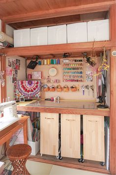 a sewing room with lots of crafting supplies on the counter and shelves above it