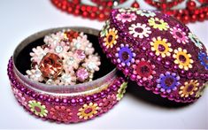 an assortment of beads and jewelry sitting in a container on a white surface with other items around it