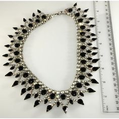 This is part of Chairish’s Costume Jewelry assortment.  Dominique collar necklace comprised of black and clear rhinestones. This statement-making piece is finished with silver colored plating. Fastens with a fold over clasp. Marked "Dominique", the mark of Dom DeTora. Dom worked for a Providence, Rhode Island company that made jewelry for both Eisenberg and Weiss. After he retired, he set up his own jewelry workshop in his home. Measures about 18" long and a little over 1 1/2" wide. Condition is excellent with sparkling stones and no wear to the plating on the back. This piece was purchased directly from the designer in the early aughts. Black Rhinestone Necklaces For Formal Occasions, Black Rhinestone Necklace For Formal Occasions, Black Rhinestone Choker Jewelry, Elegant Black Rhinestone Necklace For Formal Occasions, Elegant Black Rhinestone Necklace For Formal Events, Glamorous Black Rhinestone Necklace For Evening, Glamorous Black Jewelry With Sparkling Stones, Black Rhinestone Costume Jewelry Necklace, Black Costume Jewelry With Rhinestones