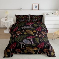 a bed covered in a black comforter with mushrooms and leaves on it, next to a night stand