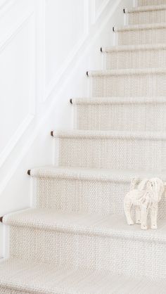 an elephant figurine sitting on the bottom of a set of white staircases