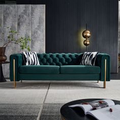 a green velvet couch with black and white pillows in a modern living room, next to a round coffee table