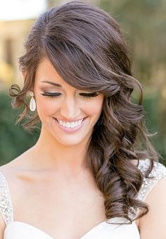 a woman in a wedding dress smiling at the camera with her long hair pulled back