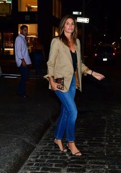 a woman standing on the side of a road at night with her hand in her pocket