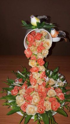 a vase filled with flowers and birds on top of a table