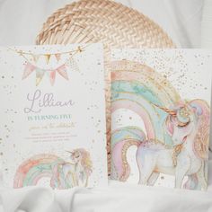 two cards with unicorns on them sitting next to a basket