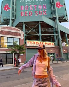 a woman walking on the sidewalk in front of fenway park boston red sox stadium