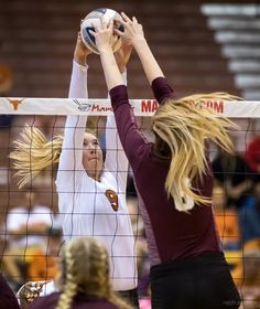 two female volleyball players trying to block the ball