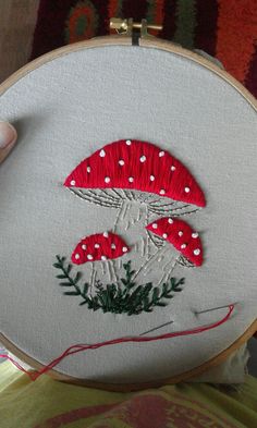 someone is stitching on to a mushroom with red and white dots in the middle