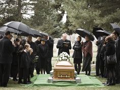 a group of people with umbrellas standing in front of a casket that reads, we are gathered here today because facebook didn't get enough likes to come