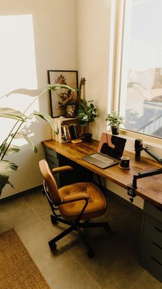 an office desk with a laptop computer on top of it next to a large window