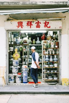 a man standing in front of a store with lots of vases