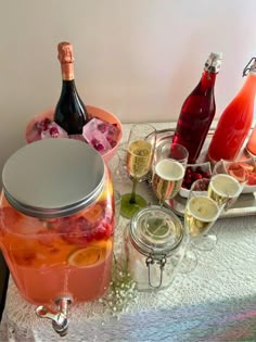 a table topped with bottles of wine and glasses filled with liquid next to ice buckets