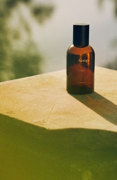 a bottle of cologne sitting on top of a wooden table next to a body of water