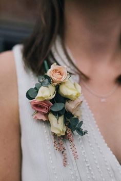 a woman wearing a white dress holding a bouquet of pink and yellow flowers in her left hand