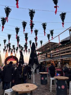 many people are walking around with umbrellas hanging from the ceiling and tables in front of them