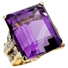 Ring size: 11 An absolute showstopper of a ring! This massive amethyst solitaire cocktail ring is set in luxurious yellow gold and accented by dazzling diamond detailing along the sides. The vibrant purple hue of the emerald cut amethyst really pops on the finger in its high profile setting, demanding the viewers attention. You will adore this spectacular piece. Ring size: 11 Metal: 14K Yellow Gold Weight: 19.9 grams Natural Amethyst: 34.85 ctw Amethyst cut: Emerald Amethyst color: Purple Natura Amethyst Cocktail Ring, Amethyst Color, Vibrant Purple, Purple Hues, Diamond Color, Diamond Clarity, Cocktail Ring, Diamond Cut, Cocktail Rings