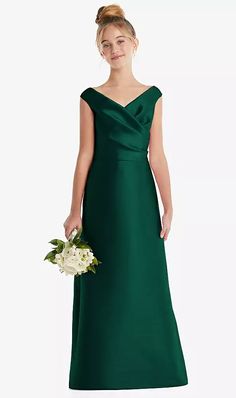 a woman in a green bridesmaid dress holding a white bouquet and posing for the camera