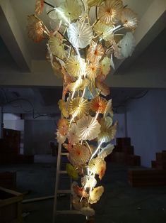 a sculpture made out of glass with flowers hanging from it's sides in a room