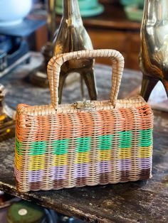 Step back in time with this adorable 1960s wicker purse.  It features a charming basket weave texture with a striped design in orange, lilac, yellow, and brown colors.   It is hinged at the bottom and closes with a gold fold over, twist clasp.  The interior is fully lined fabric with a made in Hong Kong label.  The bottom side has two bag feet.  This handbag has a perfect size for summer outings. Wonderful vintage condition with two small holes on the fabric.  The coating on the metal clasp is a bit opaque, I have not attempted to clean.  Review photos closely as, they are part of my description.  Please send me a message through Etsy with any questions. This purse is an absolute vintage treasure to own.  Enjoy! Dimensions- 6 1/2" tall x 10 1/2" tall including handle, 10 1/2" wide. -Please 60s Purse, Wicker Purse, Retro Purse, Recycle Box, Trending Fashion, Basket Weave, Yellow And Brown, Antique Items, Stripes Design