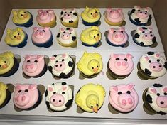 cupcakes decorated with farm animals and pigs are on display in a box for sale