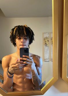 a shirtless man taking a selfie in front of a mirror with his cell phone