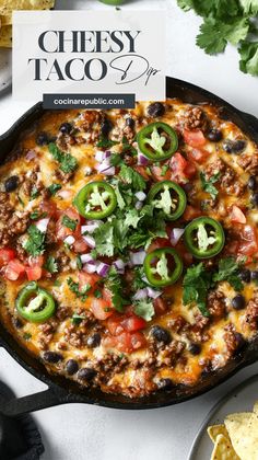 a cheesy taco dip in a cast iron skillet with tortilla chips on the side