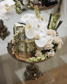 an arrangement of flowers and books is displayed on a glass stand in front of a mirror