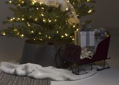 a small christmas tree in a metal container with lights on the top and presents under it