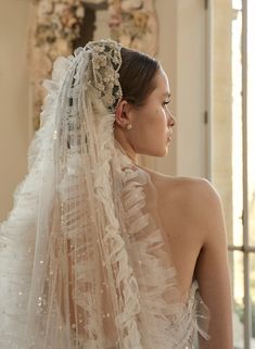 a woman in a wedding dress with a veil on her head looking off into the distance