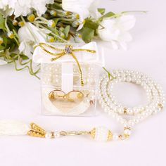 two bracelets and a necklace in a gift box with flowers on the table next to it