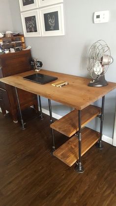 a wooden desk sitting in the corner of a room next to a wall with pictures on it