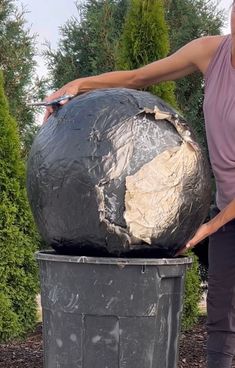 a woman standing next to a trash can with a large piece of paper on it