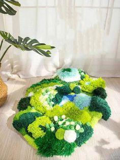 a green and white rug sitting on top of a wooden floor next to a potted plant