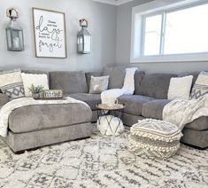 a living room with gray couches and pillows on the floor, white rugs