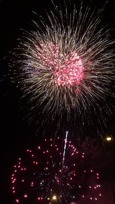 fireworks are lit up in the night sky with red and white lights on it's sides