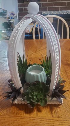 an arrangement of succulents and other plants sits on a wooden table