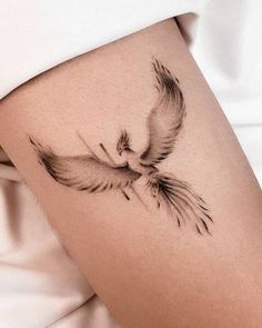 a woman's thigh with a bird tattoo on the side of her leg that is black and white