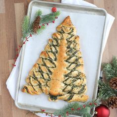 a christmas tree shaped pastry sitting on top of a baking sheet next to pine cones