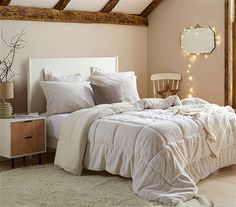 a white bed in a bedroom next to a window with string lights on the wall