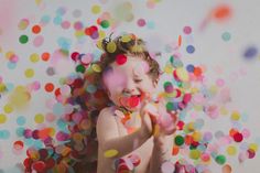 a baby is surrounded by confetti and streamers in the air with her mouth open