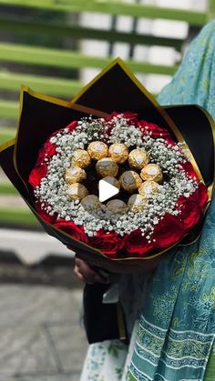 a woman holding a bouquet of flowers with chocolates in it's center,