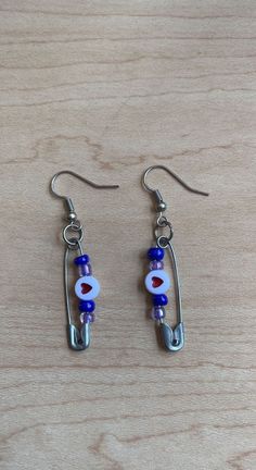 Handmade safety pin earrings with blue and purple beads, with a heart bead in the center. Heart Safety Pin, Safety Pin Jewelry Patterns, Washer Crafts, Safety Pin Jewelry, Pin Earrings, Safety Pin Earrings, Purple Beads, Loom Pattern, Recycled Art