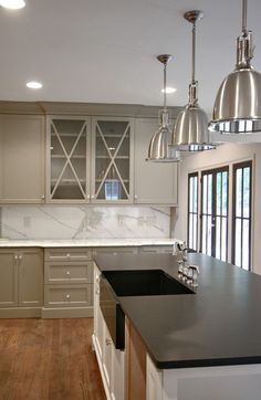 a large kitchen with an island in the middle and two pendant lights hanging from the ceiling