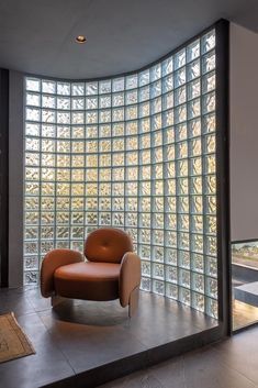 an orange chair sitting in front of a large window with glass blocks on the wall